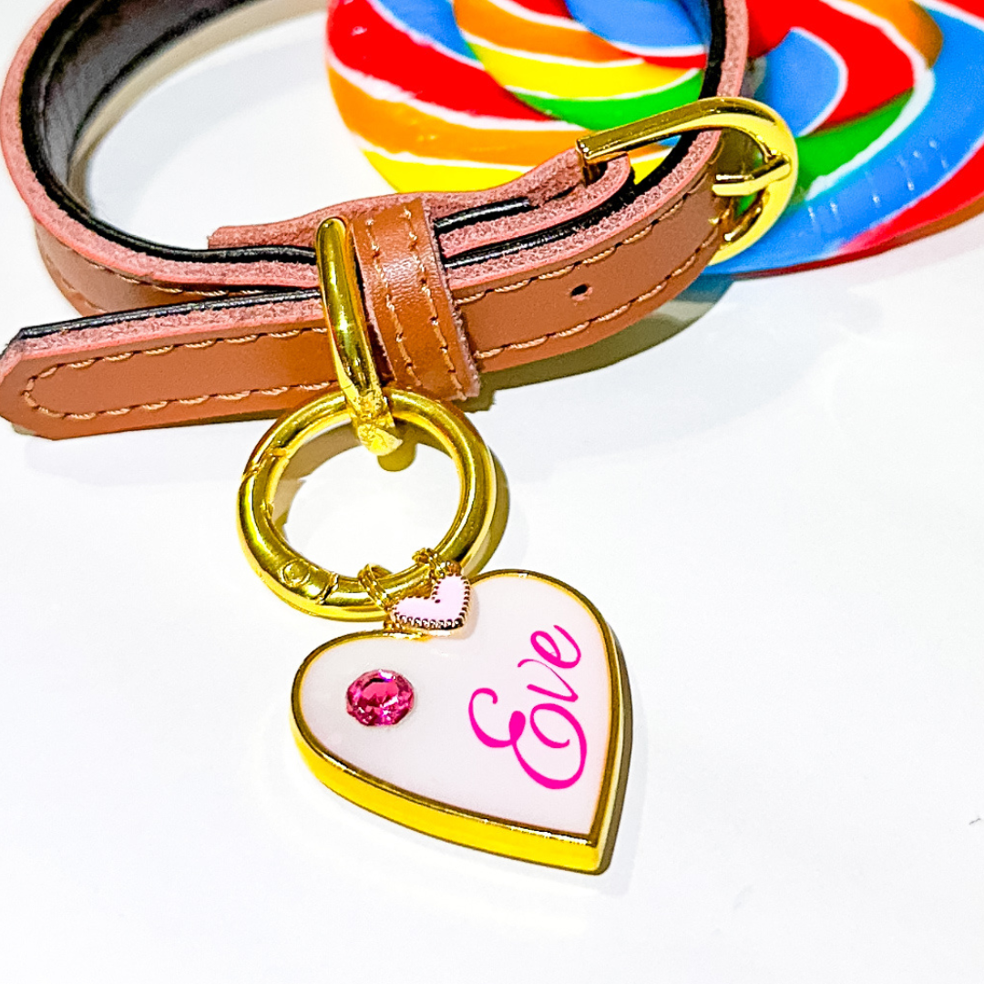 White heart-shaped pet ID tag with gold-plated stainless steel hardware and pink cubic zirconia crystal.