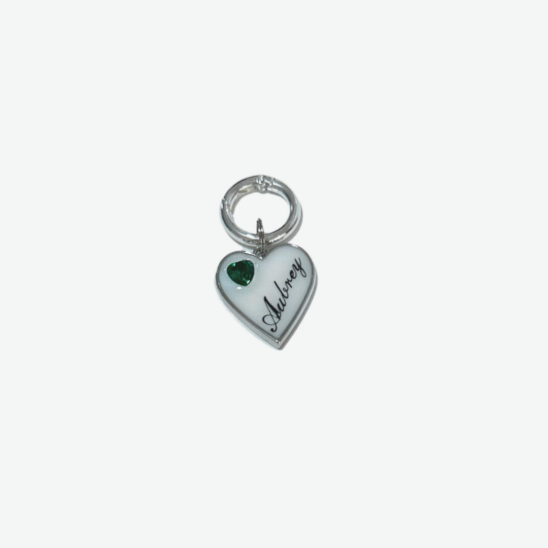 White heart-shaped pet ID tag with silver stainless steel hardware and emerald green heart-shaped cubic zirconia crystal.