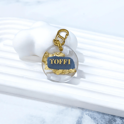 Round pet ID tag with clear resin, steele grey blue, gold leaf, and gold-plated stainless steel hardware, complimentary gold-plated stainless steel S-clasp.