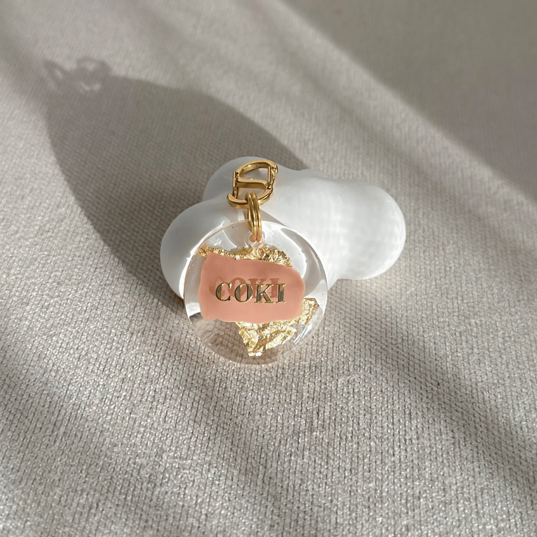 Round pet ID tag with clear resin, espresso pink, gold leaf, and gold-plated stainless steel hardware, complimentary gold-plated stainless steel S-clasp.
