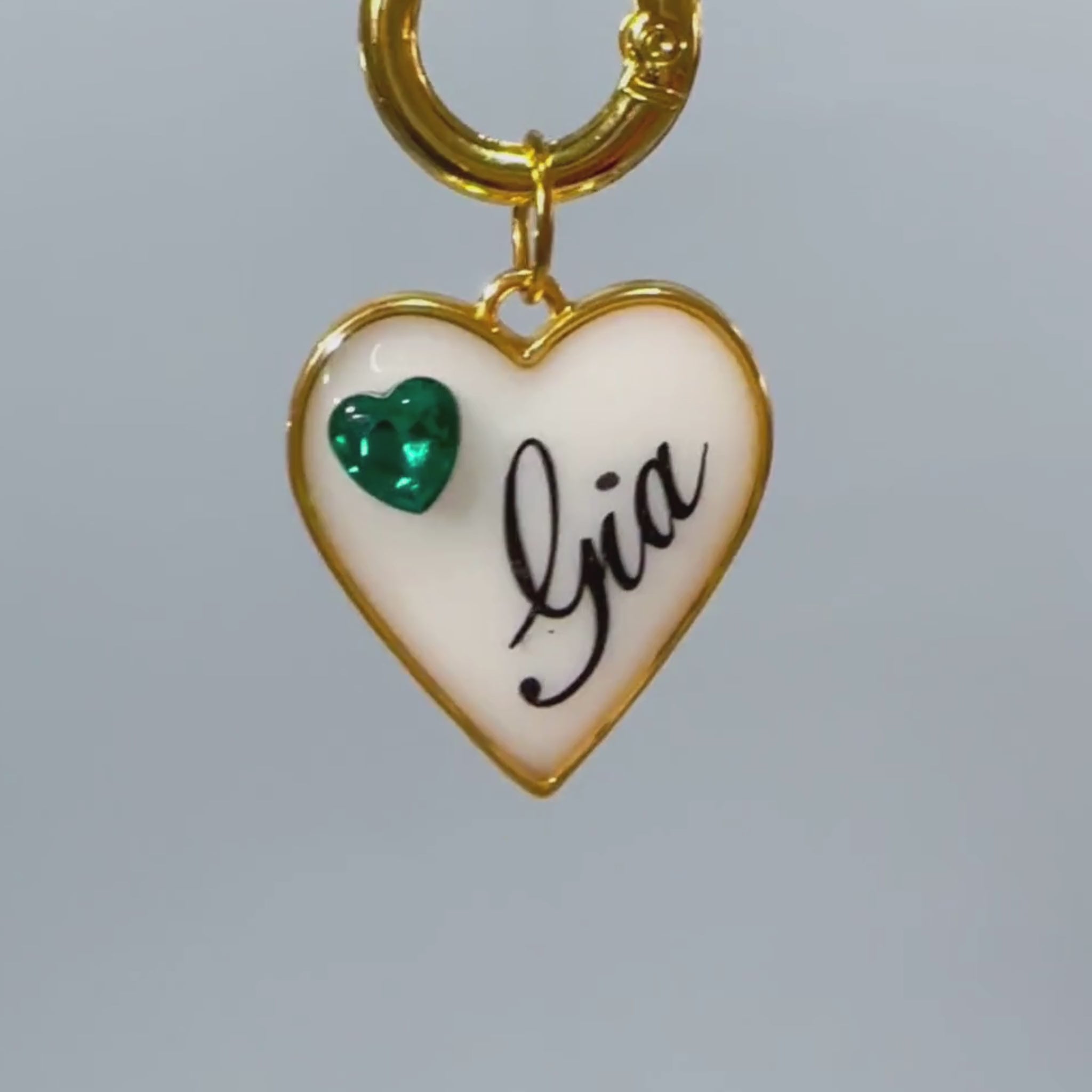 White heart-shaped pet ID tag with gold-plated stainless steel hardware and emerald green heart-shaped cubic zirconia crystal.