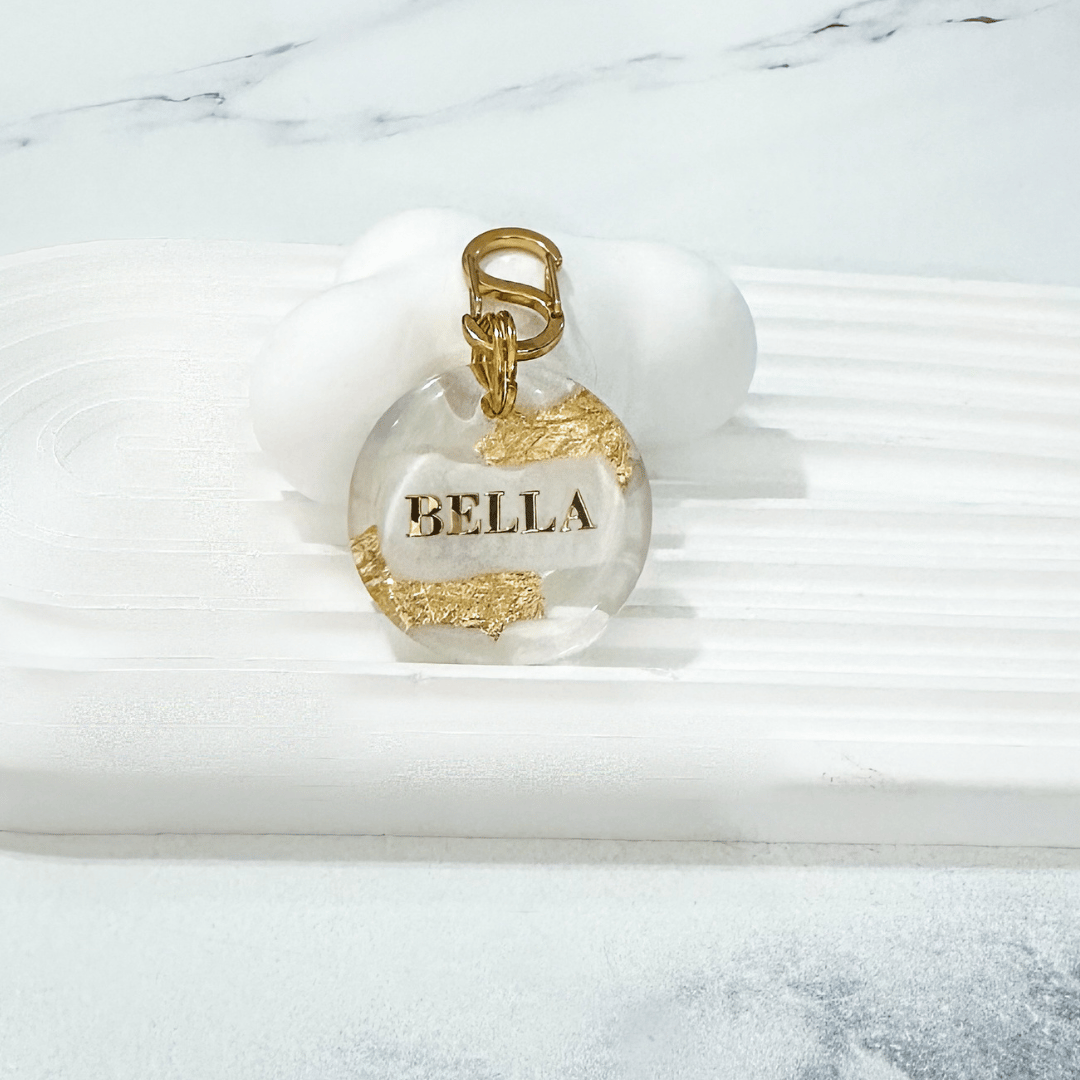 Round pet ID tag with clear resin, white, gold leaf, and gold-plated stainless steel hardware, complimentary gold-plated stainless steel S-clasp.